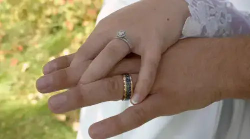 Two hands placed on top of one another with wedding rings
